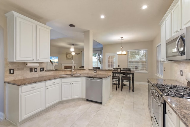 kitchen featuring sink, decorative light fixtures, appliances with stainless steel finishes, kitchen peninsula, and white cabinets