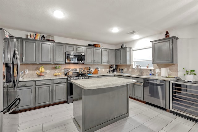 kitchen featuring wine cooler, sink, gray cabinetry, a center island, and stainless steel appliances