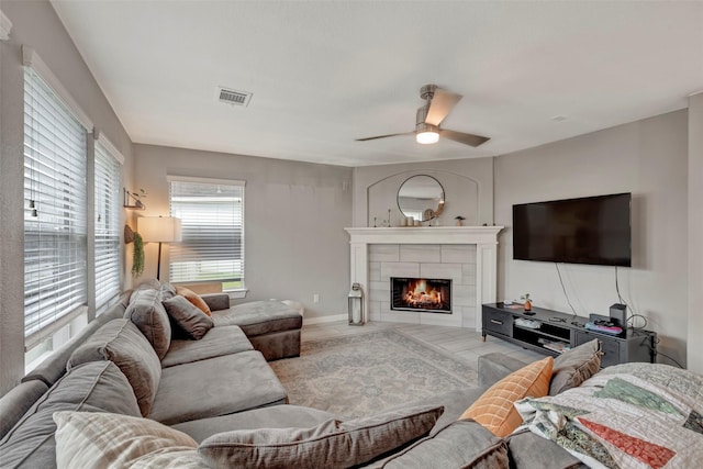 living room featuring ceiling fan and a tiled fireplace