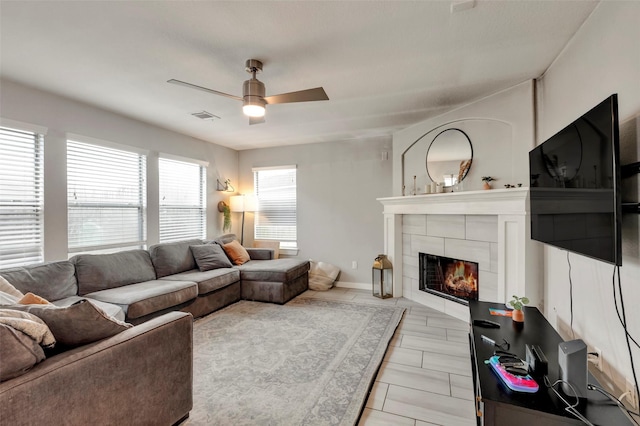 tiled living room with a fireplace and ceiling fan