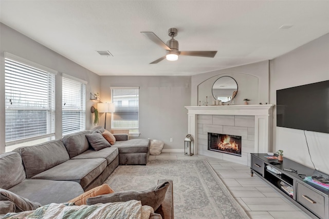 living room featuring ceiling fan and a tile fireplace