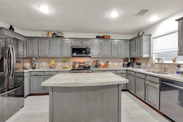 kitchen featuring appliances with stainless steel finishes, a center island, sink, and gray cabinetry