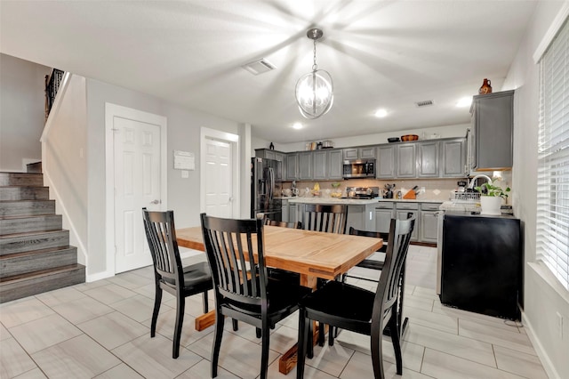 dining space with an inviting chandelier, sink, and light tile patterned floors