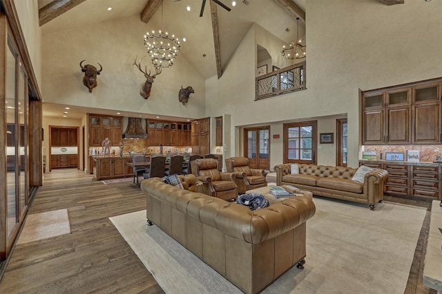 living room with lofted ceiling with beams, light wood-type flooring, and an inviting chandelier