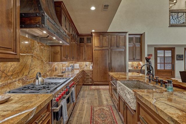 kitchen featuring sink, double oven range, custom range hood, light stone countertops, and hardwood / wood-style floors