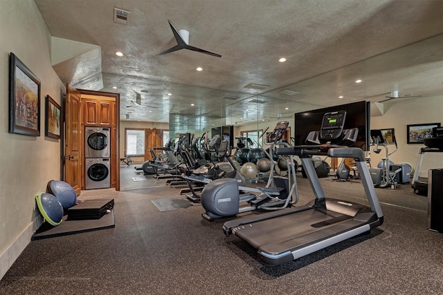 workout area with stacked washer / dryer and a textured ceiling