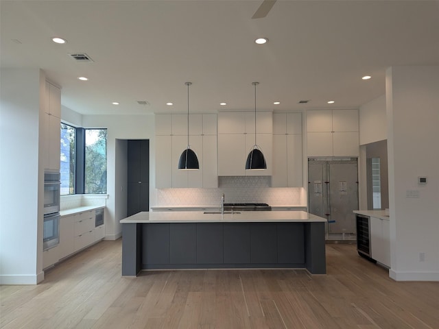 kitchen with white cabinetry, a spacious island, sink, and pendant lighting