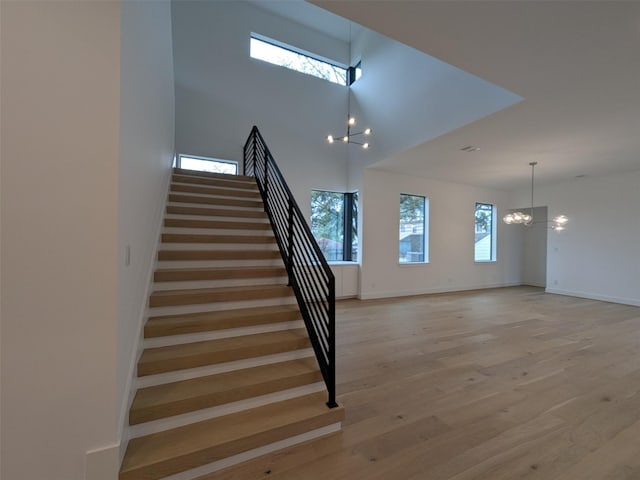 stairs featuring wood-type flooring and a notable chandelier