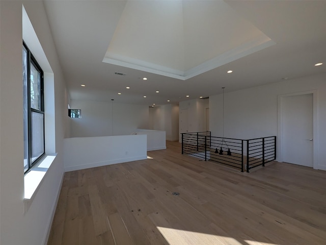 spare room featuring a raised ceiling and light wood-type flooring