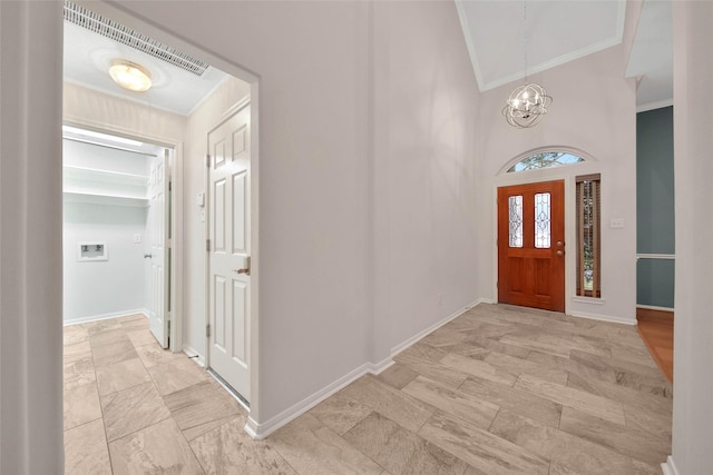 entryway featuring crown molding, high vaulted ceiling, and a notable chandelier