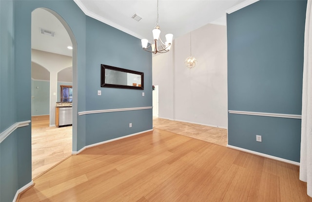 spare room with an inviting chandelier, crown molding, and hardwood / wood-style floors