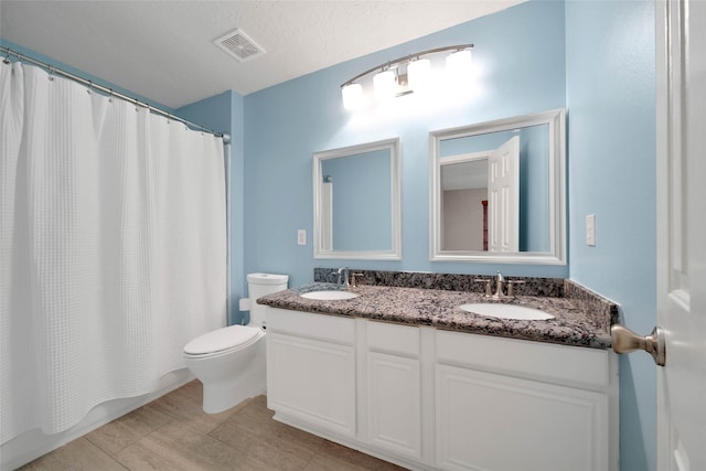 full bathroom with vanity, toilet, shower / tub combo, and a textured ceiling