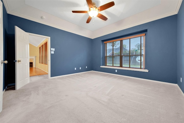 spare room with ceiling fan, ornamental molding, a tray ceiling, and light carpet