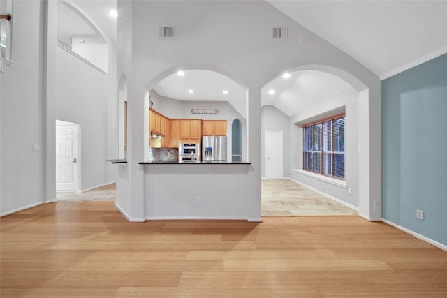 kitchen with light hardwood / wood-style flooring, high vaulted ceiling, stainless steel refrigerator with ice dispenser, light brown cabinetry, and decorative backsplash