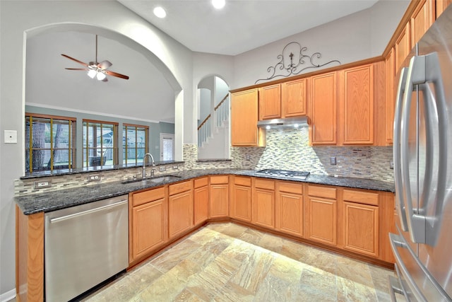 kitchen featuring sink, ceiling fan, appliances with stainless steel finishes, dark stone countertops, and tasteful backsplash