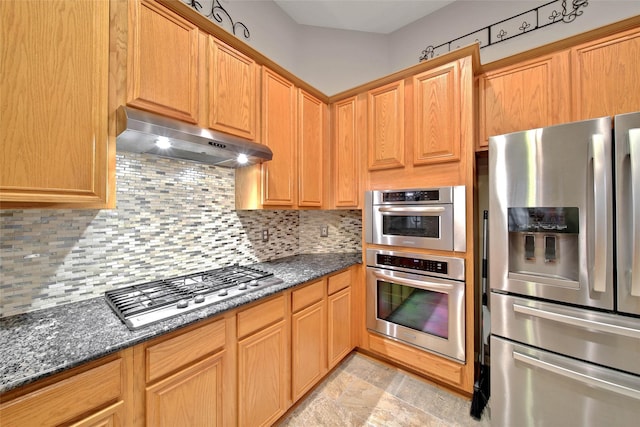 kitchen with stainless steel appliances, decorative backsplash, and dark stone countertops