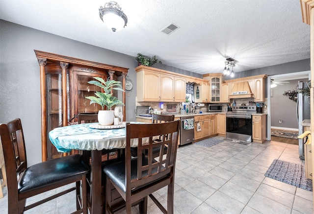 kitchen featuring premium range hood, appliances with stainless steel finishes, sink, light tile patterned floors, and light brown cabinets