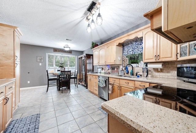 kitchen featuring stainless steel appliances, decorative light fixtures, light brown cabinetry, and sink