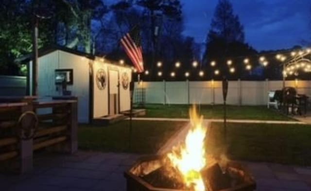 patio at night featuring an outdoor structure and a fire pit