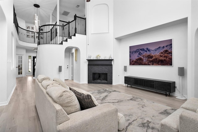 living room featuring a tile fireplace, wood-type flooring, and a towering ceiling