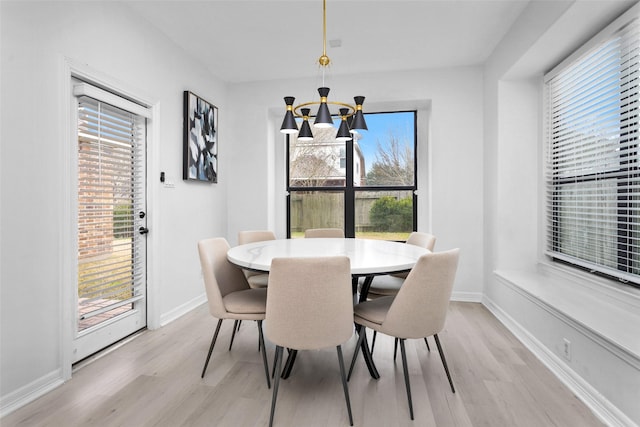 dining room with a wealth of natural light, light hardwood / wood-style floors, and a chandelier