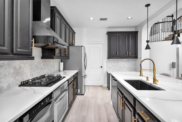 kitchen with wall chimney range hood, sink, hanging light fixtures, light stone counters, and black appliances