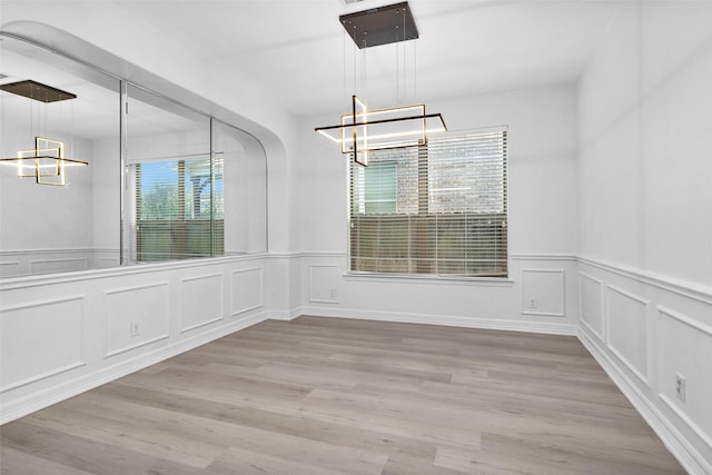 unfurnished dining area with hardwood / wood-style flooring, plenty of natural light, and a chandelier