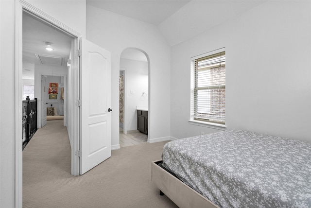 bedroom featuring light colored carpet, connected bathroom, and vaulted ceiling