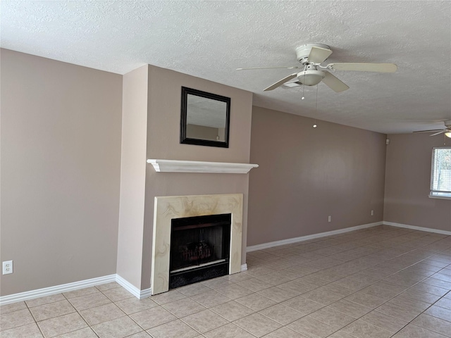 unfurnished living room featuring a fireplace, a ceiling fan, light tile patterned flooring, a textured ceiling, and baseboards