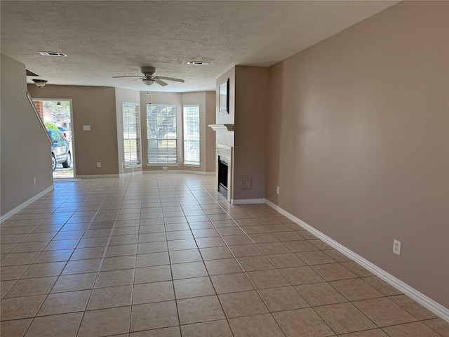 unfurnished living room with ceiling fan, a textured ceiling, and light tile patterned floors