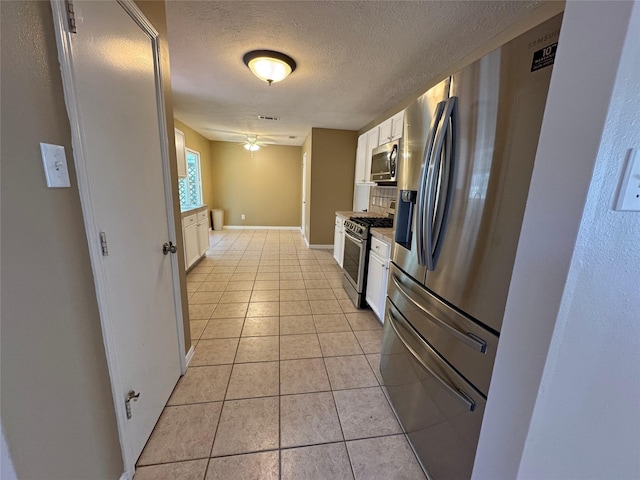 kitchen featuring appliances with stainless steel finishes, white cabinetry, backsplash, and light tile patterned floors