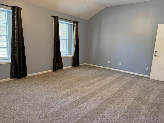 carpeted spare room with a healthy amount of sunlight and vaulted ceiling