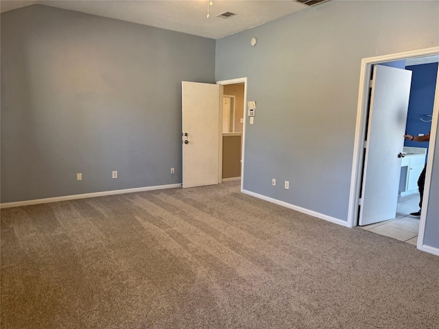 carpeted empty room with vaulted ceiling