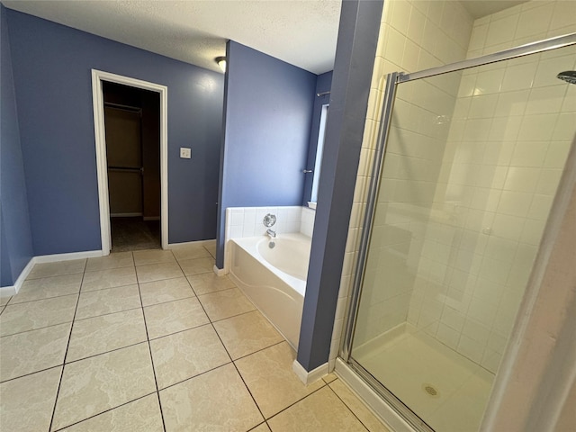 bathroom with a garden tub, a shower stall, a textured ceiling, tile patterned flooring, and baseboards