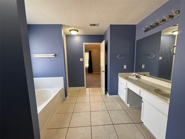 bathroom with a washtub, vanity, tile patterned floors, and a textured ceiling