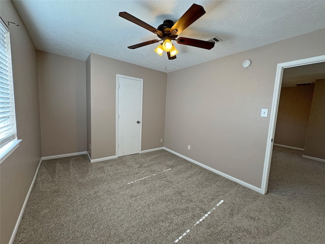 unfurnished bedroom with light carpet, ceiling fan, and a textured ceiling