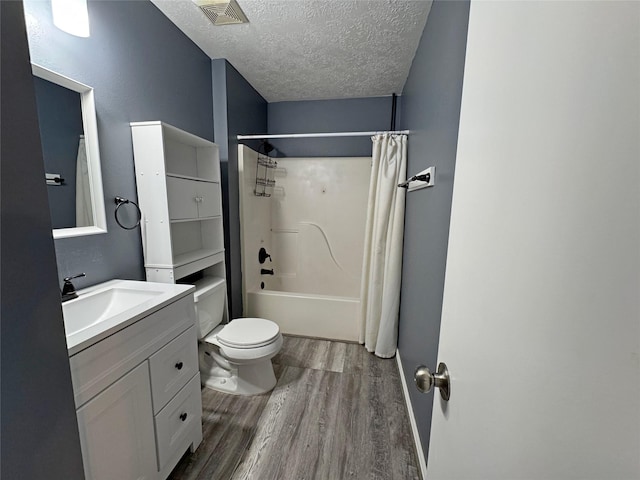 full bathroom with shower / bath combo, vanity, wood-type flooring, a textured ceiling, and toilet