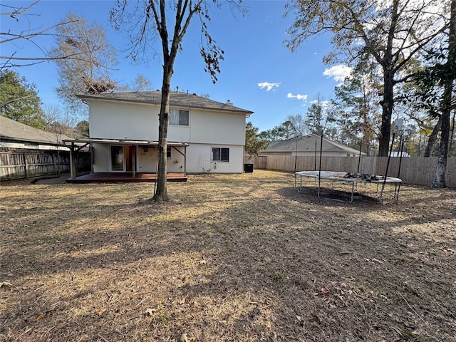 back of house with a fenced backyard, a trampoline, and a wooden deck