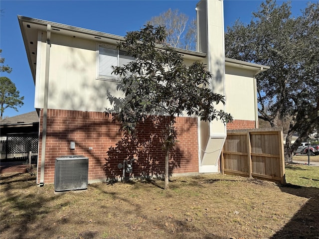 view of home's exterior featuring central air condition unit, fence, and brick siding