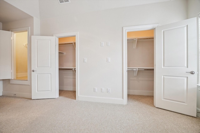 unfurnished bedroom with a walk in closet and light colored carpet