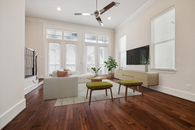 living room with a high ceiling, crown molding, dark wood-type flooring, and ceiling fan