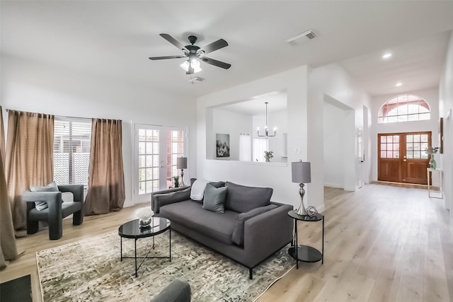 living room with a healthy amount of sunlight, ceiling fan with notable chandelier, and light wood-type flooring