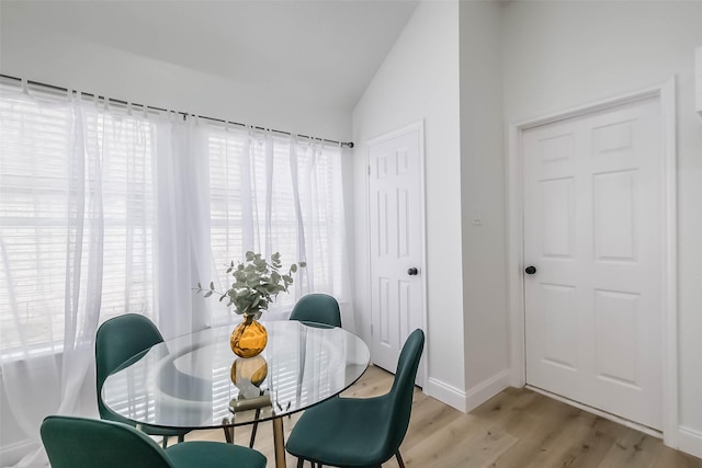 dining room with vaulted ceiling and light wood-type flooring