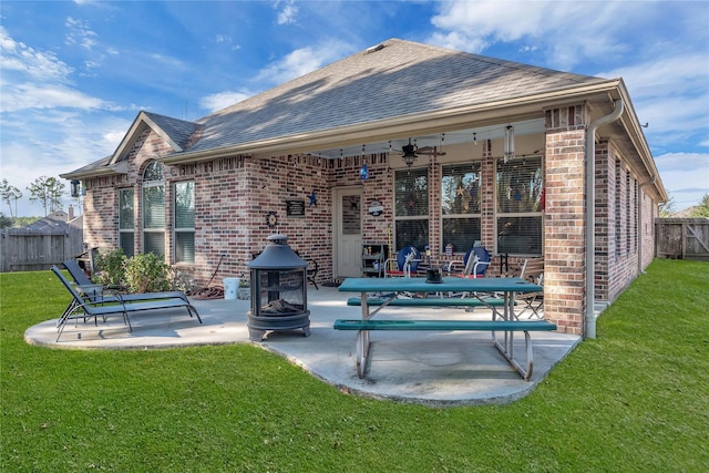 back of property with a patio, a fire pit, ceiling fan, and a lawn