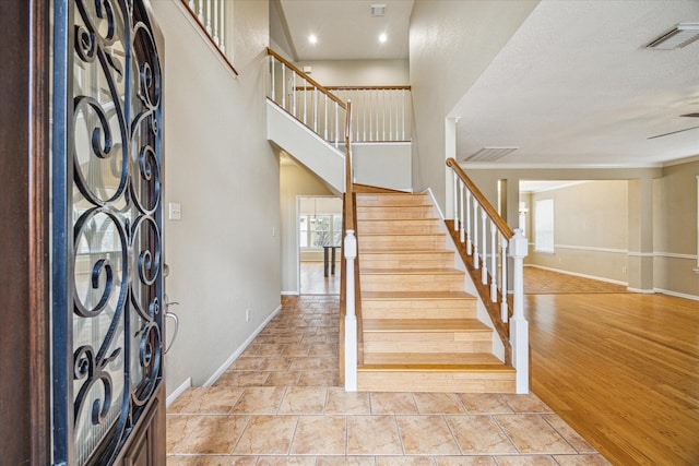 stairs with crown molding, hardwood / wood-style floors, and a towering ceiling