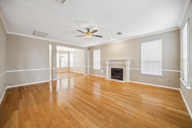 unfurnished living room featuring ceiling fan with notable chandelier, light wood finished floors, a tile fireplace, and baseboards