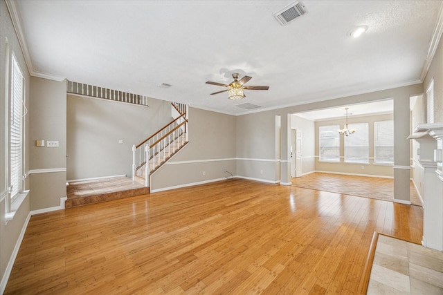 unfurnished living room with ceiling fan with notable chandelier, crown molding, light wood finished floors, and stairs