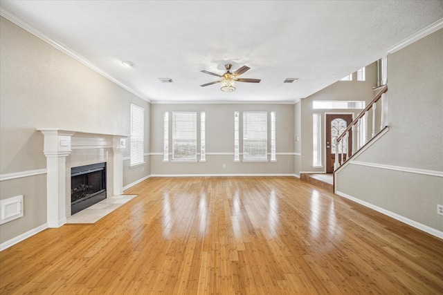 unfurnished living room with a fireplace, visible vents, stairs, ornamental molding, and light wood finished floors