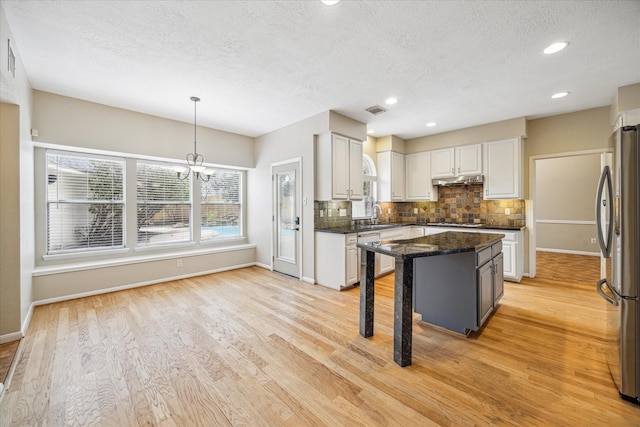 kitchen with a sink, visible vents, appliances with stainless steel finishes, light wood finished floors, and tasteful backsplash