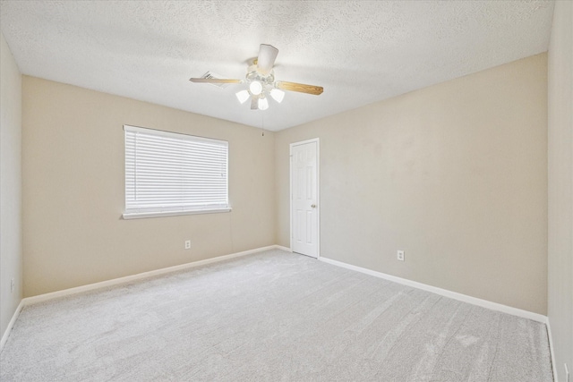 carpeted empty room with a textured ceiling, a ceiling fan, and baseboards